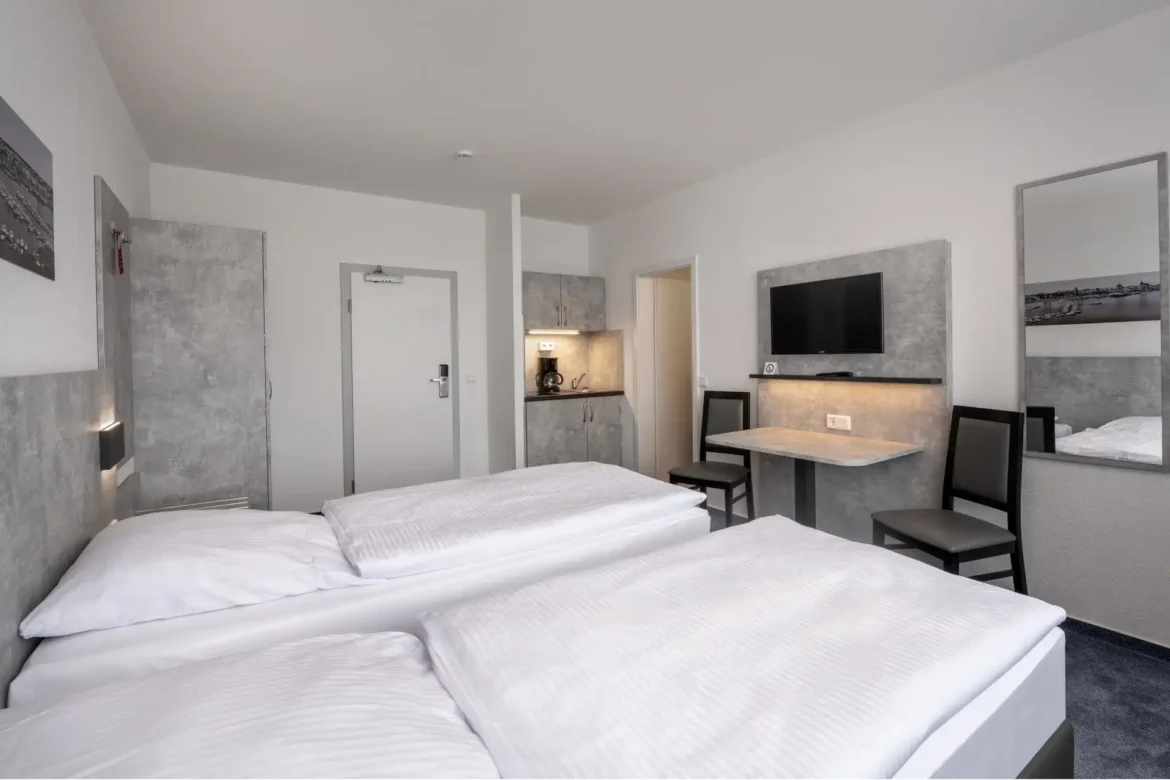 Helles Zweibettzimmer Standard mit Mikro-Küche, Fernseher und zwei getrennten Betten – perfekt für Kurzreisen.